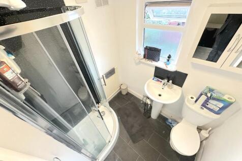 Bright, modern bathroom with a curved glass sho...