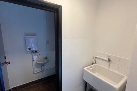 An empty arch with white lining and a WC cubicle to the front.