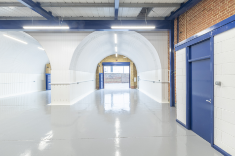 The front of an arch, with high level glazing, an open electric roller shutter entrance big enough for vehicle access, and a pedestrian door.