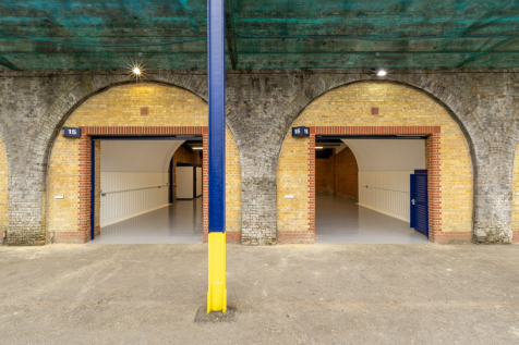 The front of an arch with an open electric roller shutter entrance big enough for vehicle access.