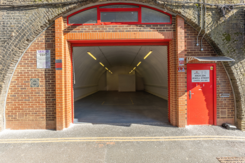 The front of an arch, with high level glazing, and an open electric roller shutter entrance big enough for vehicle access. 