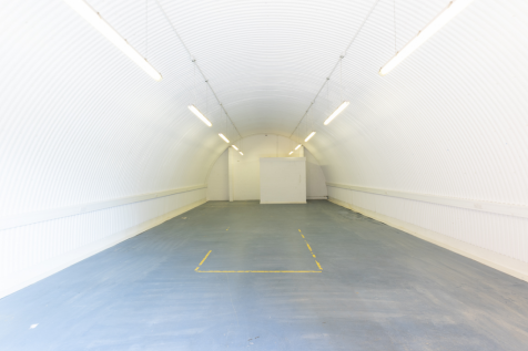 An empty arch with white lining and a WC cubicle to the back.