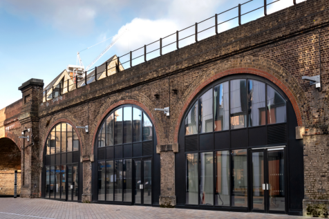The front of an arch, with a fully glazed frontage and door allowing you to see into the arch interior.