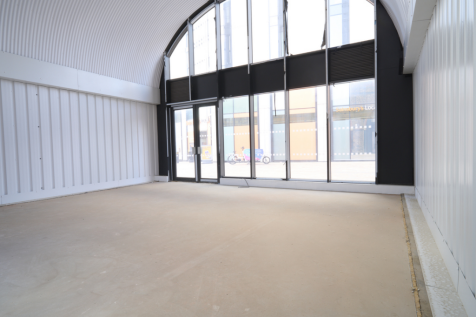An empty arch with white lining and full height glazing to the front.