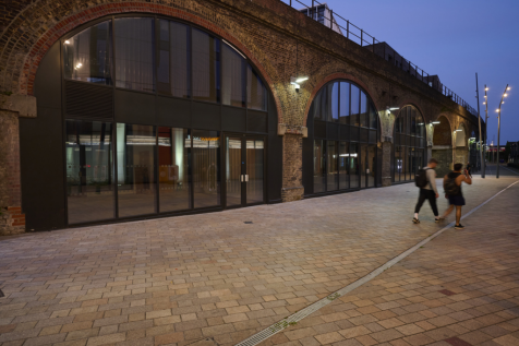 The front of an arch, with a fully glazed frontage and door allowing you to see into the arch interior.