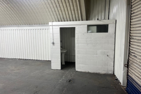 An empty arch with white lining and a WC cubicle to the front.