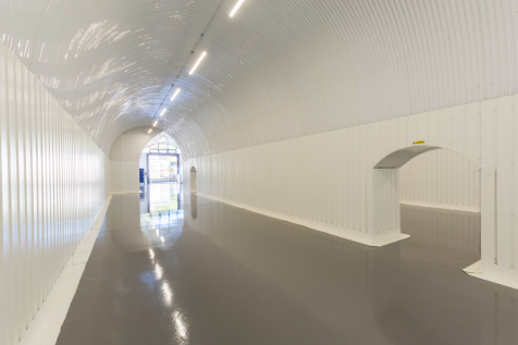 The front of an arch, with high level glazing, a closed electric roller shutter entrance big enough for vehicle access, and a pedestrian door.