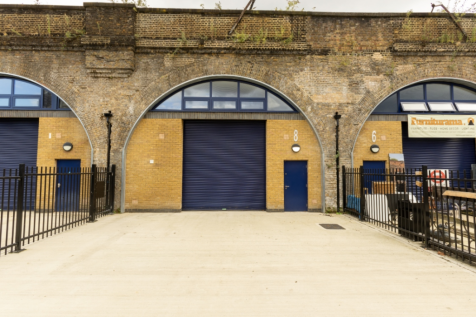 The front of an arch, with high level glazing, a closed electric roller shutter entrance big enough for vehicle access, and a pedestrian door.