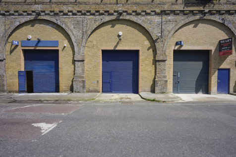 The front of an arch with a closed electric roller shutter entrance big enough for vehicle access. 