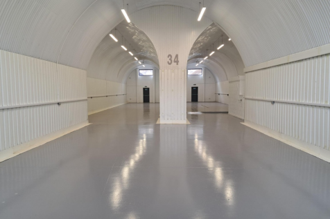 An empty arch with white lining and a WC cubicle to the front.