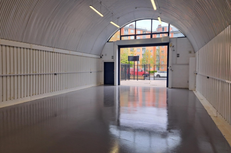 The front of an arch, with high level glazing, an open electric roller shutter entrance big enough for vehicle access, and a pedestrian door.