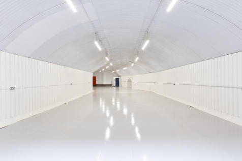 An empty arch with white lining and a WC cubicle to the back.