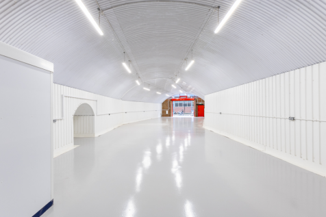 An empty arch with white lining and a WC cubicle to the back.
