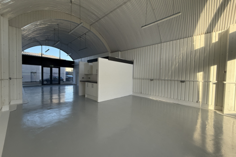 An empty arch with white lining and full height glazing to the front.
