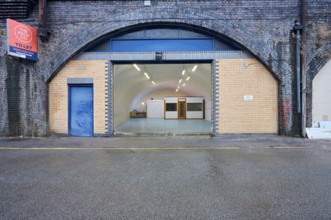 The front of an arch with an open electric roller shutter entrance big enough for vehicle access.