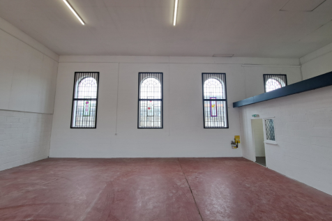 The interior of a warehouse unit, facing the front electric roller shutter, which is closed and large enough for vehicle access.