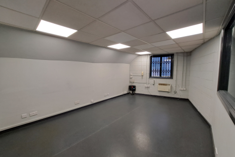 An empty arch with white lining, facing the front electric roller shutter entrance, which is closed.