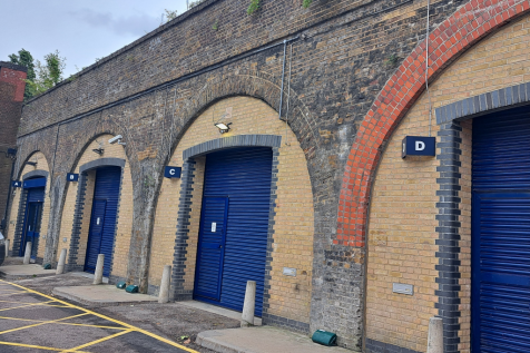 An estate, with multiple arches next to each other. The arches have closed electric roller shutter entrances.