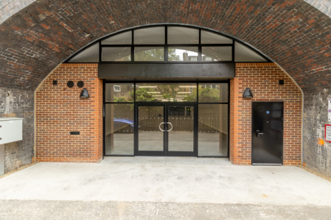 The front of an arch, with a fully glazed frontage and door allowing you to see into the arch interior.
