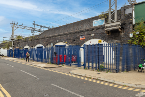 The front of an arch with a closed electric roller shutter entrance big enough for vehicle access, and separate pedestrian door.

