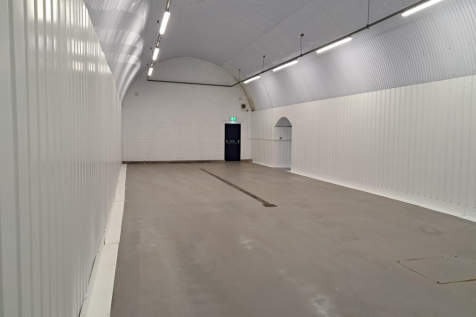 An empty arch with white lining and a fire escape door at the back.