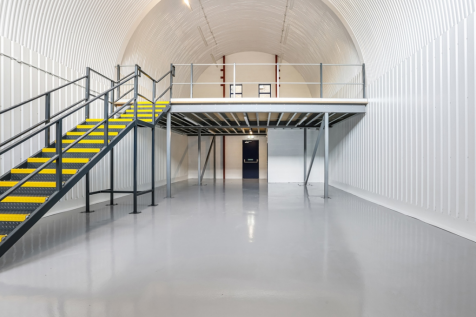 An arch with lining and a ground floor level and a mezzanine level, connected by stairs.