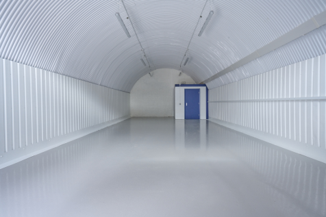An empty arch with white lining and a WC cubicle to the back.