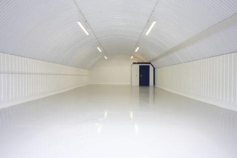 An empty arch with white lining and a WC cubicle to the back.