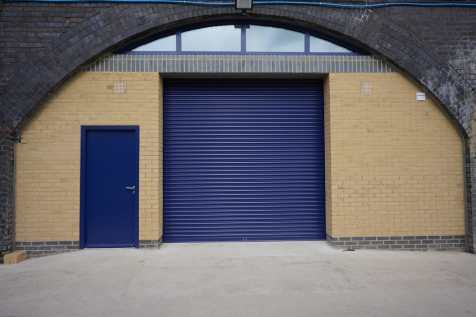 The front of an arch, with high level glazing, a closed electric roller shutter entrance big enough for vehicle access, and a pedestrian door.