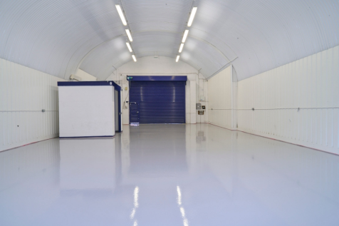 An empty arch with white lining and a WC cubicle to the front.