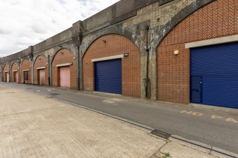 An estate, with multiple arches next to each other. The arches have closed electric roller shutter entrances.