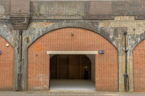 The front of an arch with an open electric roller shutter entrance big enough for vehicle access.