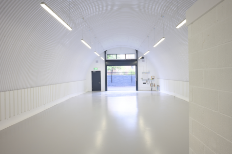 The front of an arch with an open electric roller shutter entrance big enough for vehicle access, and separate pedestrian door.