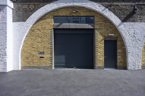 The front of an arch, with high level glazing, a closed electric roller shutter entrance big enough for vehicle access, and a pedestrian door.