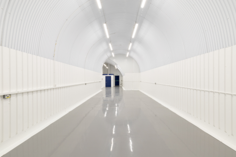 An empty arch with white lining and a WC cubicle to the back.