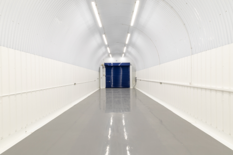 An empty arch with white lining and a WC cubicle to the back.