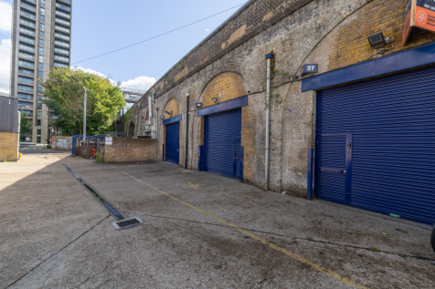 The front of an arch with a closed electric roller shutter entrance big enough for vehicle access, and separate pedestrian door.

