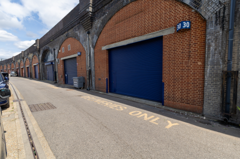 The front of an arch with a closed electric roller shutter entrance big enough for vehicle access, and separate pedestrian door.

