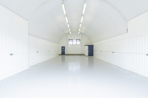 An empty arch with white lining and a WC cubicle to the back.