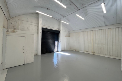 An empty arch with white lining and a WC cubicle to the front.