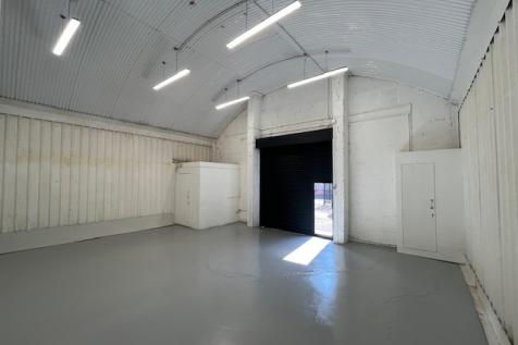 An empty arch with white lining and a WC cubicle to the front.