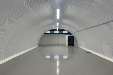 An empty arch with white lining and a WC cubicle to the back.