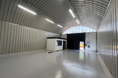 An empty arch with white lining and a WC cubicle to the front.