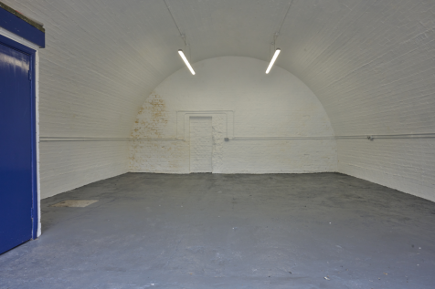 An empty arch with white lining and a WC cubicle to the front.