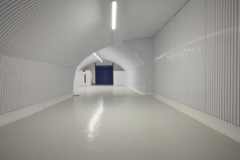 An empty arch with lining, facing the front electric roller shutter entrance, which is closed.