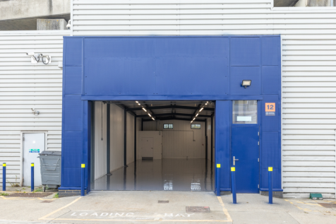 The front of an arch with an open electric roller shutter entrance big enough for vehicle access, and separate pedestrian door.