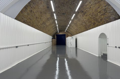The interior of a warehouse unit, facing the front electric roller shutter, which is open and large enough for vehicle access.