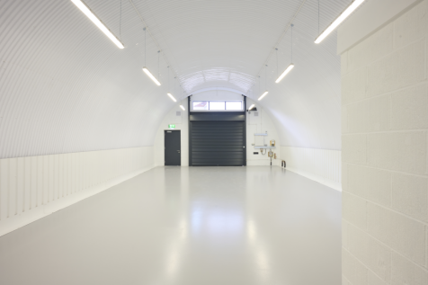 The front of an arch with an open electric roller shutter entrance big enough for vehicle access, and separate pedestrian door.