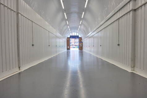 An empty arch with lining, facing the front electric roller shutter entrance, which is open.