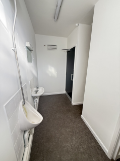 An empty arch with white lining and a WC cubicle to the back.